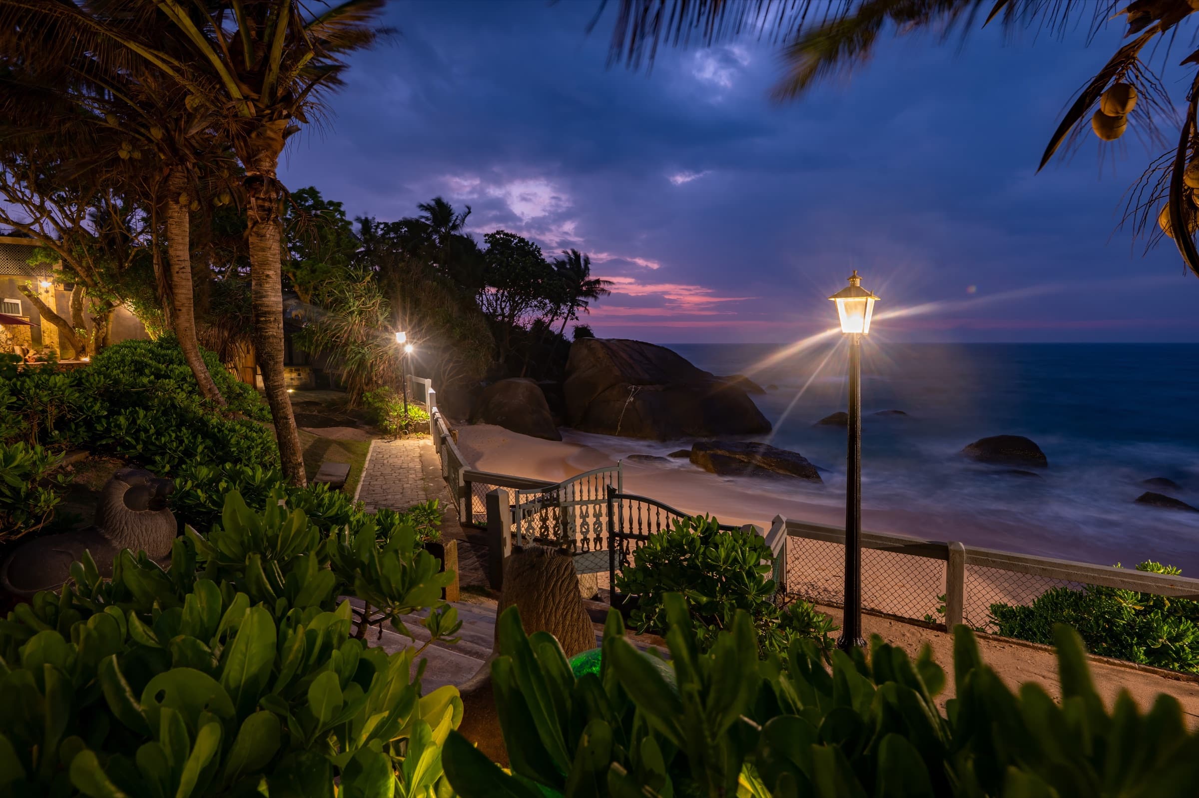 Lamp-lit boardwalk to the beach at dusk